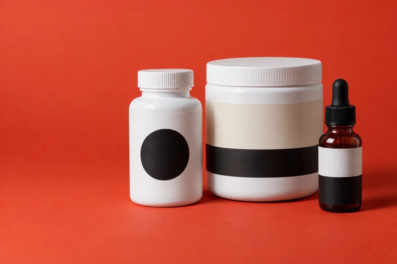 A capsule bottle, a powder tub and an amber dropper bottle, each with a black and cream label, on a red backdrop